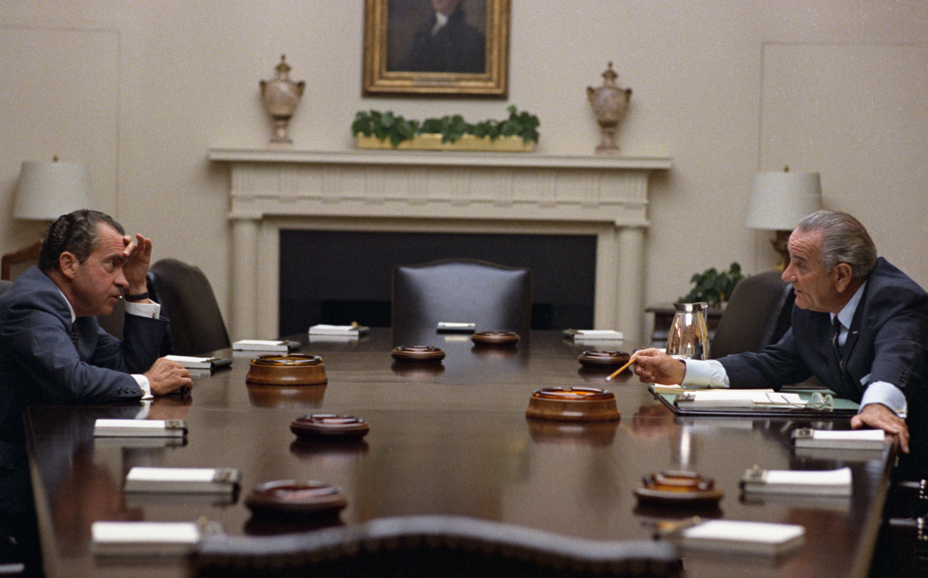 Richard Nixon on the left, listening to LBJ, on the right, making a point across a large table